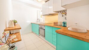 Eine moderne Küche mit türkisfarbenen Schränken, einer Holz Arbeitsplatte, einem eingebauten Ofen und einer Kaffeemaschine.