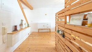 Ein Zimmer mit Holzboden, einem weißen Schrank, einem Holzregal mit einem gerahmten Bild und einer Giraffenfigur.
