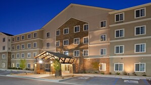 A multi-story hotel with a stone facade, a covered entrance, and a parking area with disabled parking.