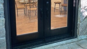 A black-framed glass door with a view of an indoor seating area with chairs and a table. - Cozy Sandy Pines Cottage Suite, right on Lake Huron in a Carolinian Forest,  (Grand Bend)