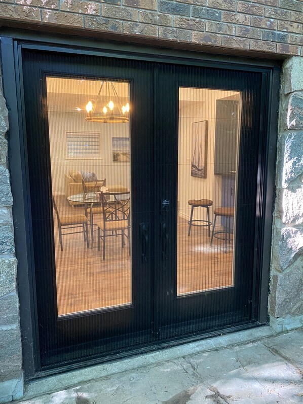 A black-framed glass door with a view of an indoor seating area with chairs and a table.