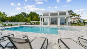Una piscina con sillones de descanso y una zona de estar cubierta.