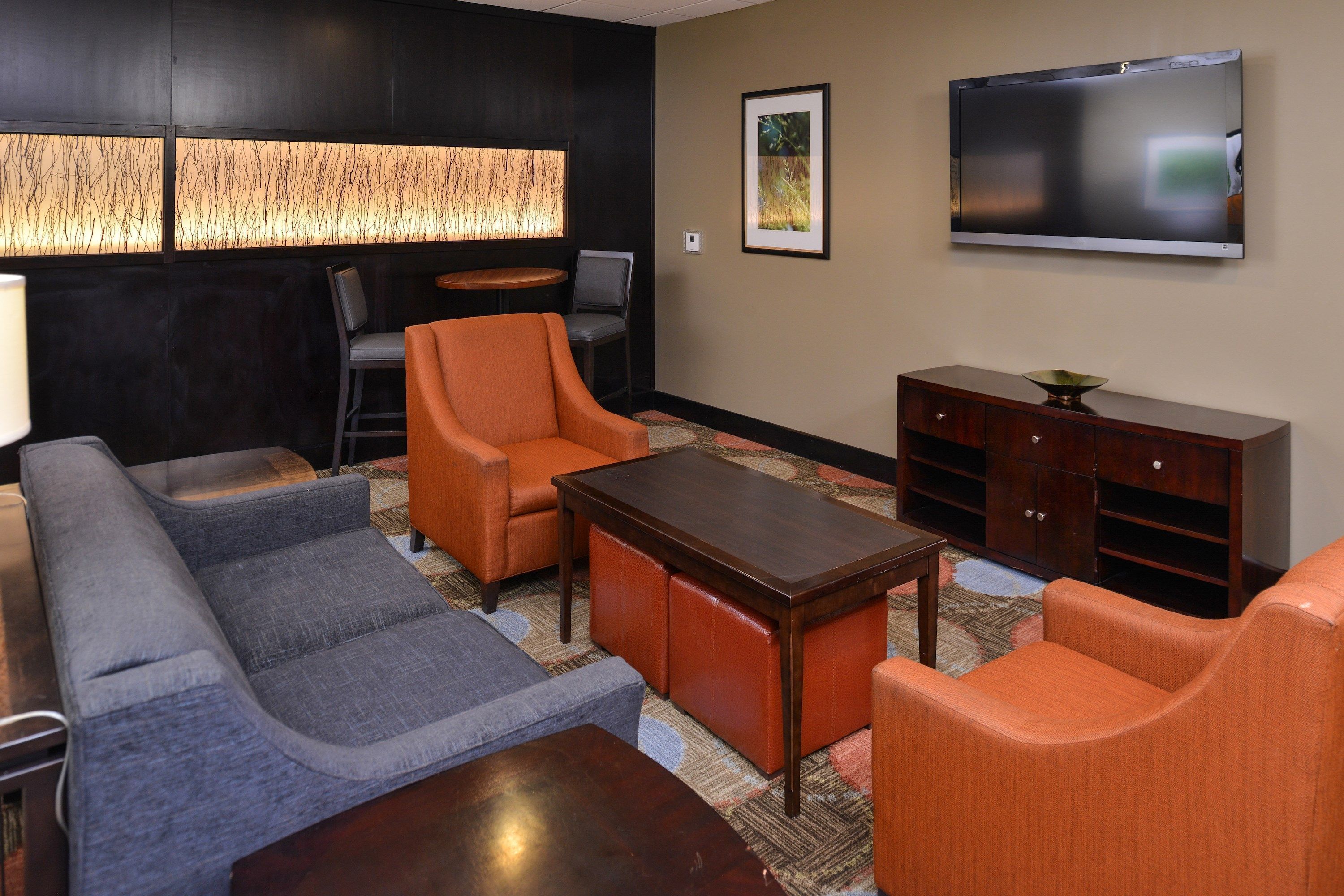 A modern living room with a sofa, armchairs, a coffee table, and a flat-screen TV mounted on the wall.