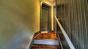 A staircase with wooden steps and a metal handrail, leading to a door with a glass panel. - Stunning Minimalist Gem | Fenced Backyard + W/D (Saint Louis)