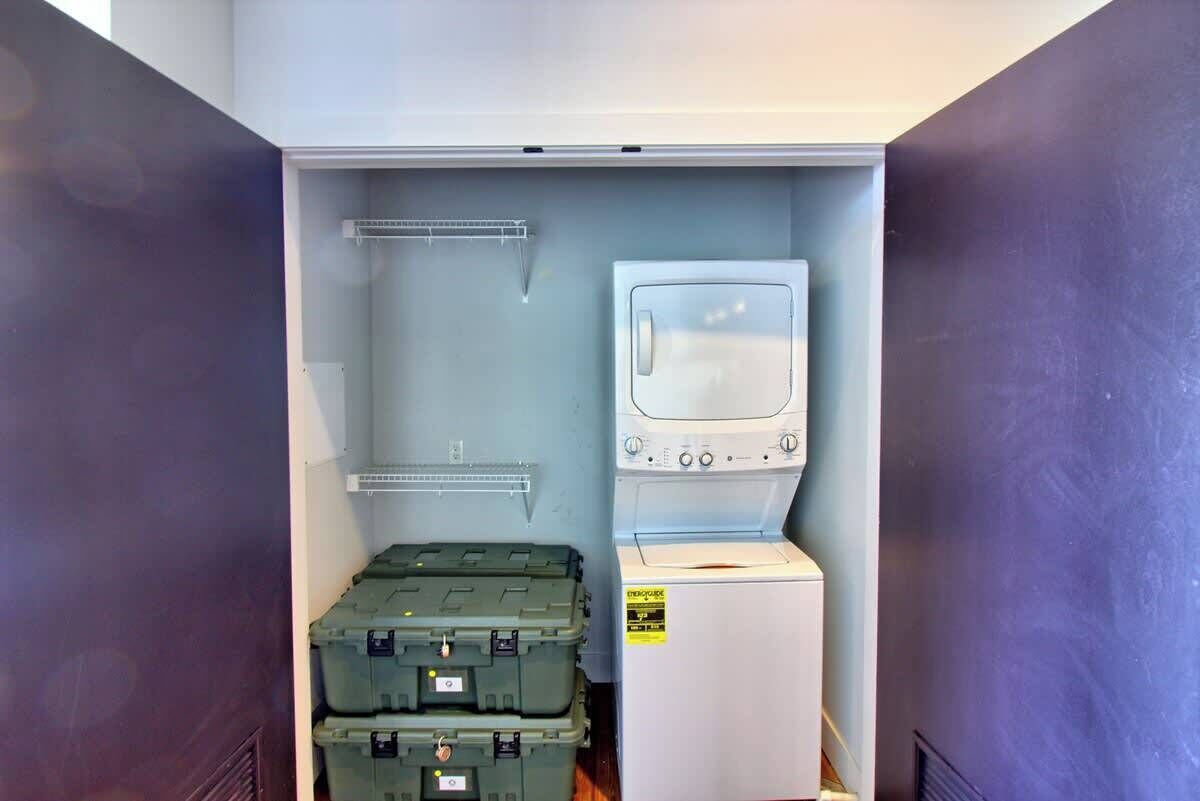 A compact laundry room with a washing machine and stacked storage bins.