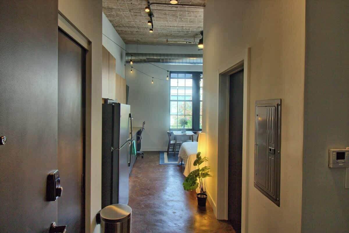 A hallway with a desk, chair, and potted plant.