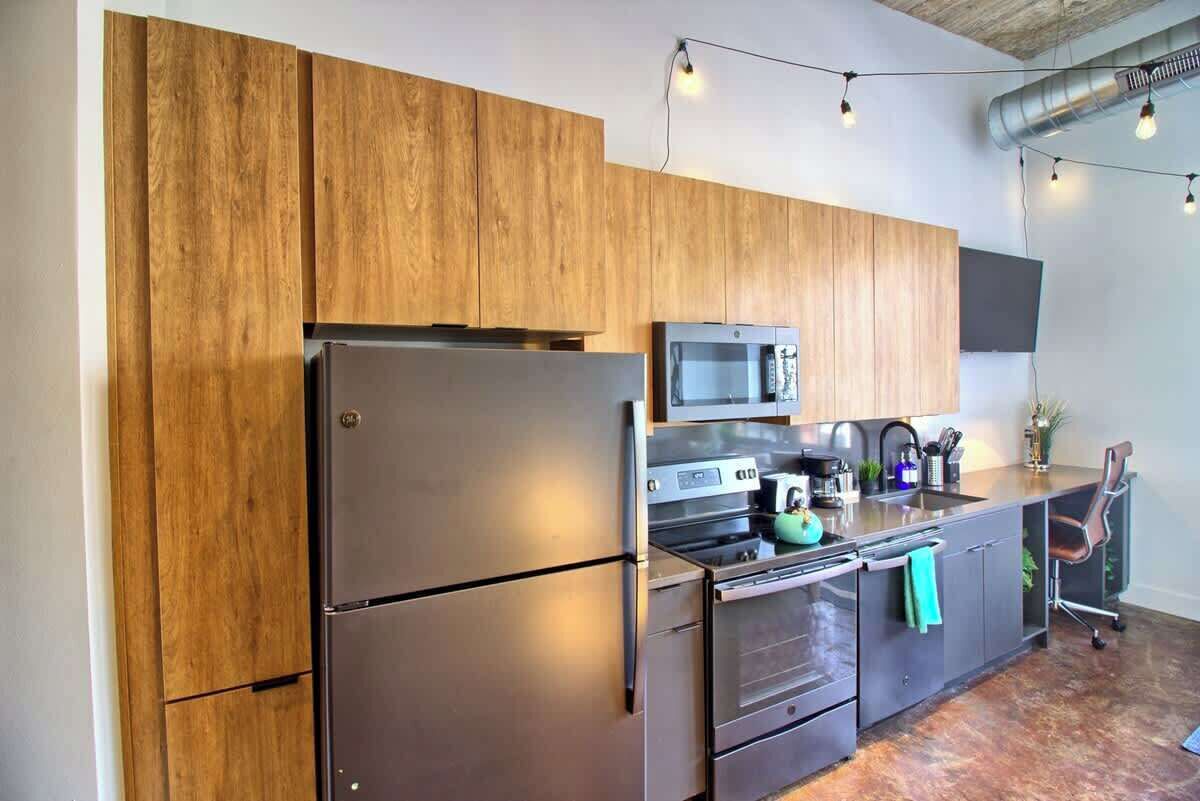 Una cocina moderna con armarios de madera, electrodomésticos de acero inoxidable y un televisor de pantalla plana montado en la pared.