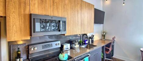 A modern kitchen with wooden cabinets, stainless steel appliances, and a built-in microwave.