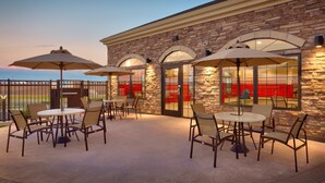 An outdoor patio with tables and chairs, stone walls, and large umbrellas. - 1 Bedroom | Fully Equipped Suite + Wi-Fi! (Cheyenne)
