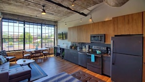 A modern kitchen with wooden cabinets, a large window, and a seating area with a sofa and chairs. - Chic Ultramodern Studio Loft w/ Designer Features (Saint Louis)