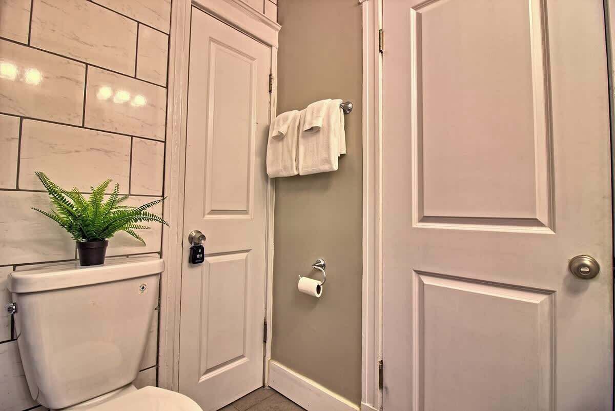 Ein Badezimmer mit Toilette, einer Pflanze, einem Handtuchhalter und einer Tür.