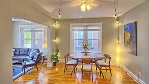 A spacious living room with a dining table, wooden chairs, a sofa, and a ceiling fan. - Irises at TG Park | Fenced Backyard+W/D+Storage (Saint Louis)
