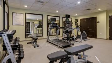 A fitness center with treadmills, elliptical machines, and weight benches.