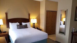 Ein Hotelzimmer mit einem großen Bett, zwei Nachttischlampen, einer Holztür und einem Spiegel an der Wand.