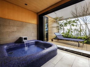 A modern spa area with a hot tub, a lounge chair, and a view of a garden through a glass door. - Mercure Hida Takayama (Takayama)