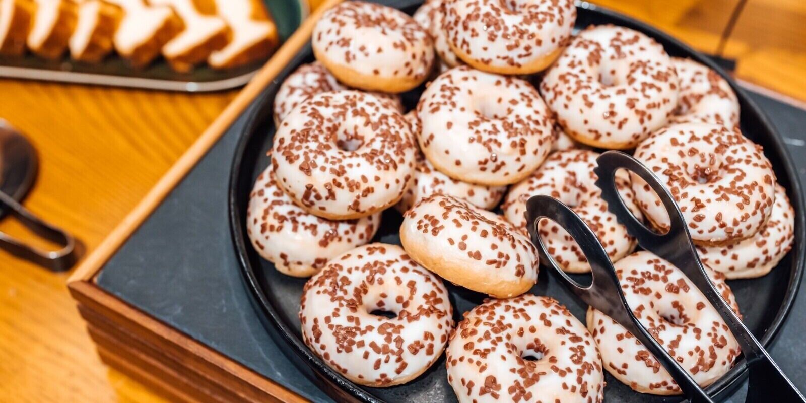A tray of white donuts with chocolate sprinkles.