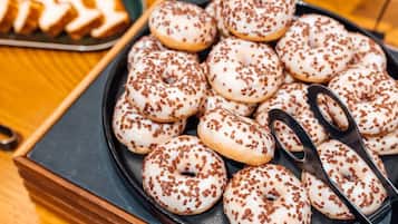 A tray of white donuts with chocolate sprinkles.