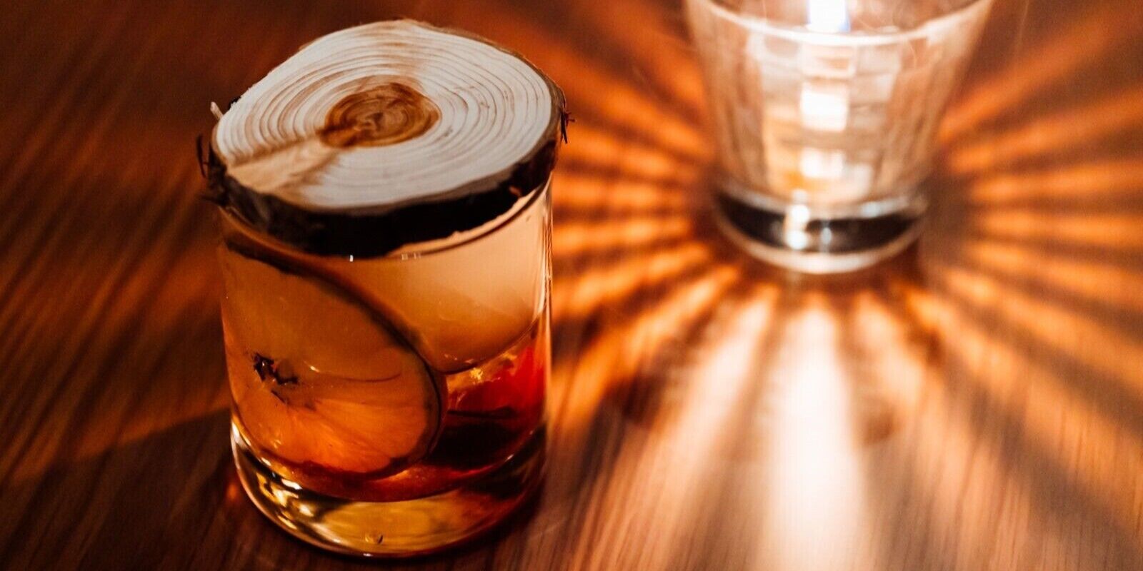 A candle in a glass holder on a wooden surface.