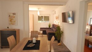 Un soggiorno moderno con un tavolo da pranzo in legno, un divano e una TV a parete.