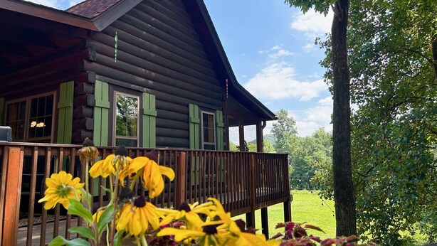 A log cabin with a wooden deck and a green railing. - Cozy Blue Skies Cabin - walk to Chimney Rock & Lake Lure (Lake Lure)