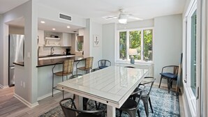 A modern kitchen with a built-in refrigerator, a dining area with a glass table and chairs, and a window with a view of greenery. - PET FRIENDLY Fairway Oaks Villa! Kiawah West Beach (Kiawah Island)
