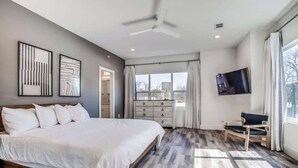 A bedroom with a bed, a dresser, a TV, and a chair.