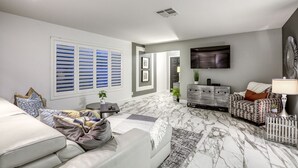 A modern living room with a sofa, a patterned rug, and a television mounted on the wall.
