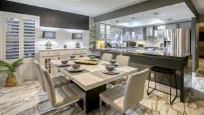 A modern kitchen with a marble countertop, stainless steel appliances, and a dining area with a marble table and chairs.