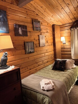 Een houten kamer met een bed, een dressoir en kunstwerken aan de muur.