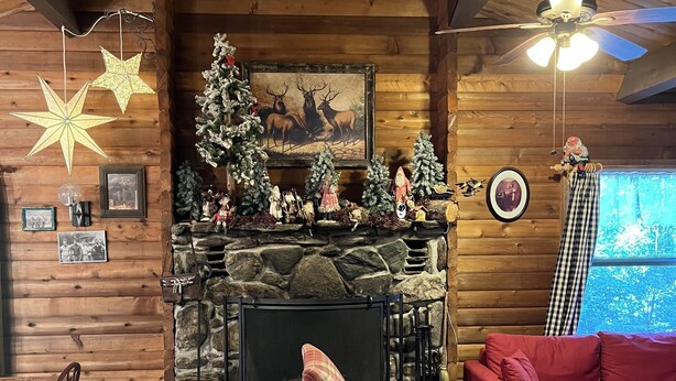 Interior acogedor de una cabaña con chimenea de piedra, paredes de madera y un sofá rojo.