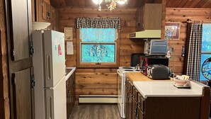 Una cocina tipo cabaña de madera con refrigerador, estufa y armarios de madera.