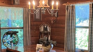 Un interior de madera con una mesa de comedor, bancos, una araña y objetos decorativos.