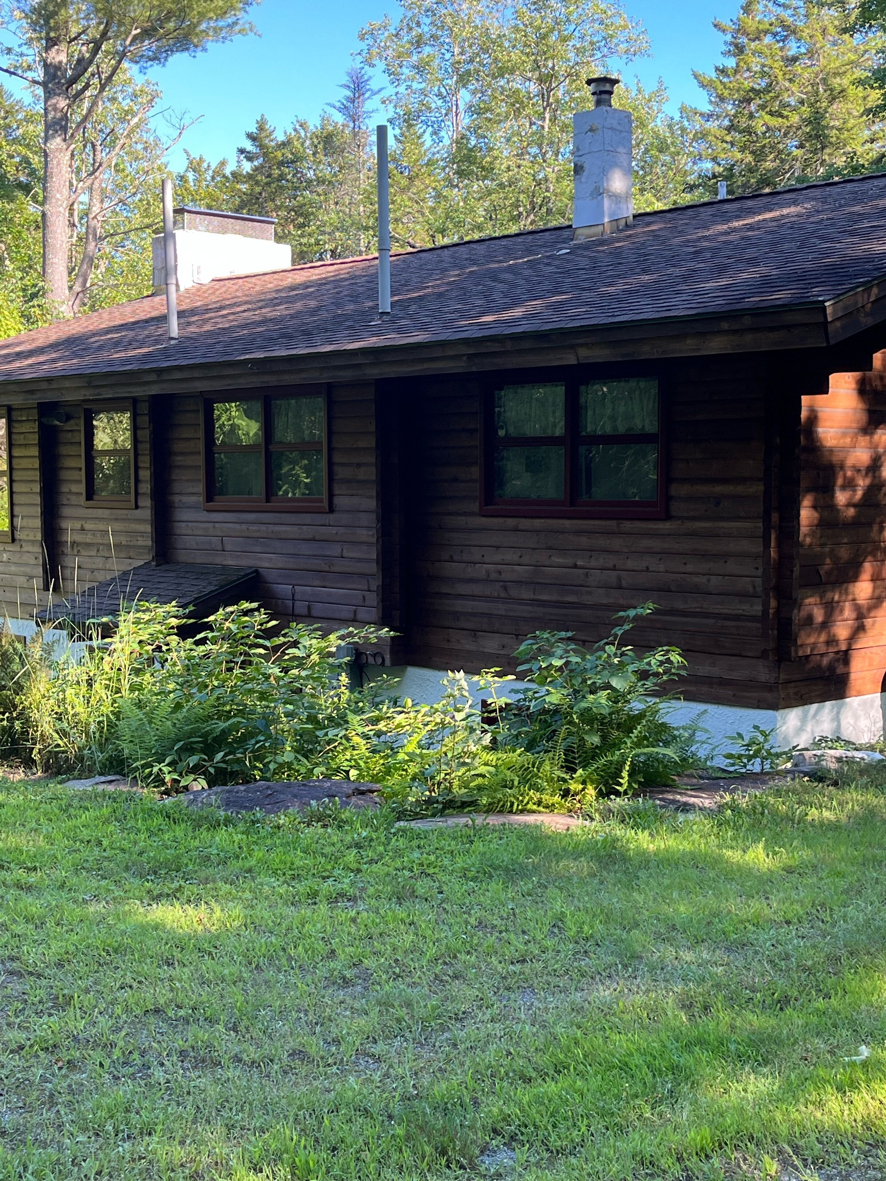 A wooden cabin with a sloped roof, multiple windows, and a chimney.