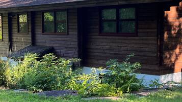 A wooden cabin with a sloped roof, multiple windows, and a chimney.