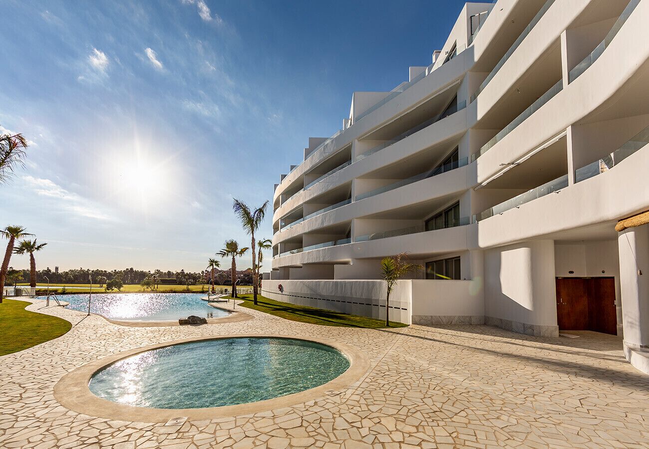 Ein modernes Hotel mit Poolbereich, mehreren Balkonen und freiem Blick auf die umliegende Landschaft.