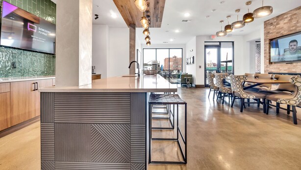 Una cocina moderna con una isla grande, techo de madera e iluminación colgante.