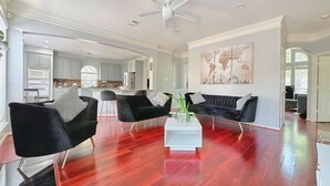 Ett rymligt vardagsrum med modern design, inrett med en svart soffgrupp, ett vitt soffbord och en takfläkt.
