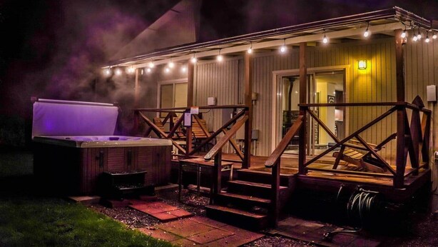 Een bubbelbad en een zitgedeelte buiten, met een overdekt terras en lichtslingers.