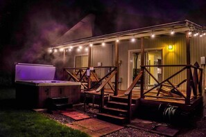 Een bubbelbad en een zitgedeelte buiten, met een overdekt terras en lichtslingers.