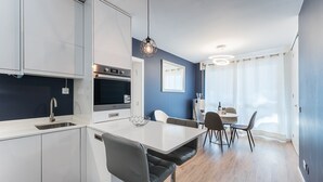 Eine moderne Küche mit weißen Schränken, einem eingebauten Backofen und einem Essbereich mit Tisch und Stühlen.