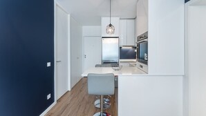 Eine moderne Küche mit weißen Schränken, einem Edelstahl-Kühlschrank und einer Bar mit Hockern.