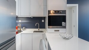 Eine kleine Küche mit Kühlschrank, Backofen und Spüle.
