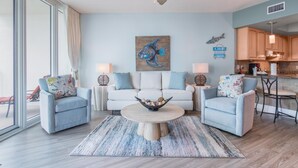 Ein Wohnzimmer mit Deckenventilator, einem Couchtisch mit Dekoration, zwei Sesseln, einer Couch und einem Bild von einem Fisch an der Wand.