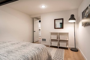 A bedroom with a bed, a standing lamp, a mirror, and a wardrobe with shelves.