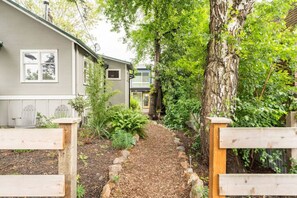 A pathway leading to a house with a small garden and a wooden fence.
