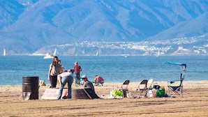 Une plage avec des gens, des chaises et un panneau d’avertissement concernant des câbles enroulés.