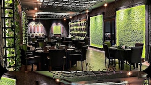 Un restaurante con varias salas de comedor, jardines verticales verdes y una pantalla grande que muestra un paisaje navideño.