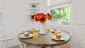 A breakfast table with orange juice, muffins, and a vase of flowers.