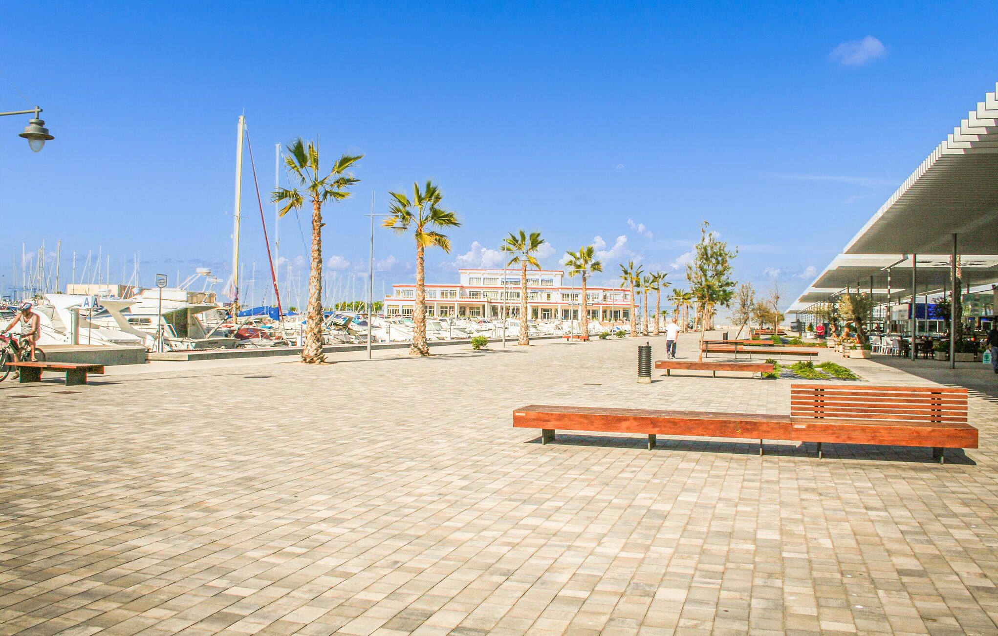 Un puerto deportivo con barcos, palmeras y un edificio de techo plano.