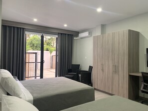 Une chambre d’hôtel avec deux lits, un bureau et une armoire.